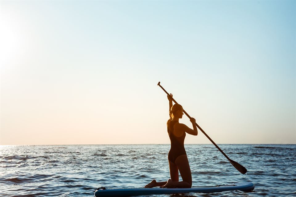 Silhouette of young beautiful girl surfing in sea at sunrise. Outdoors. paddle surf en el mar