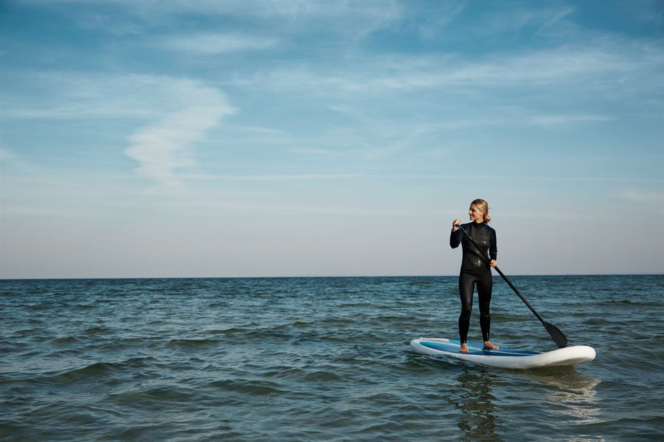 Young blonde female paddles a paddleboard at the sea paddle surf en Lanzarote